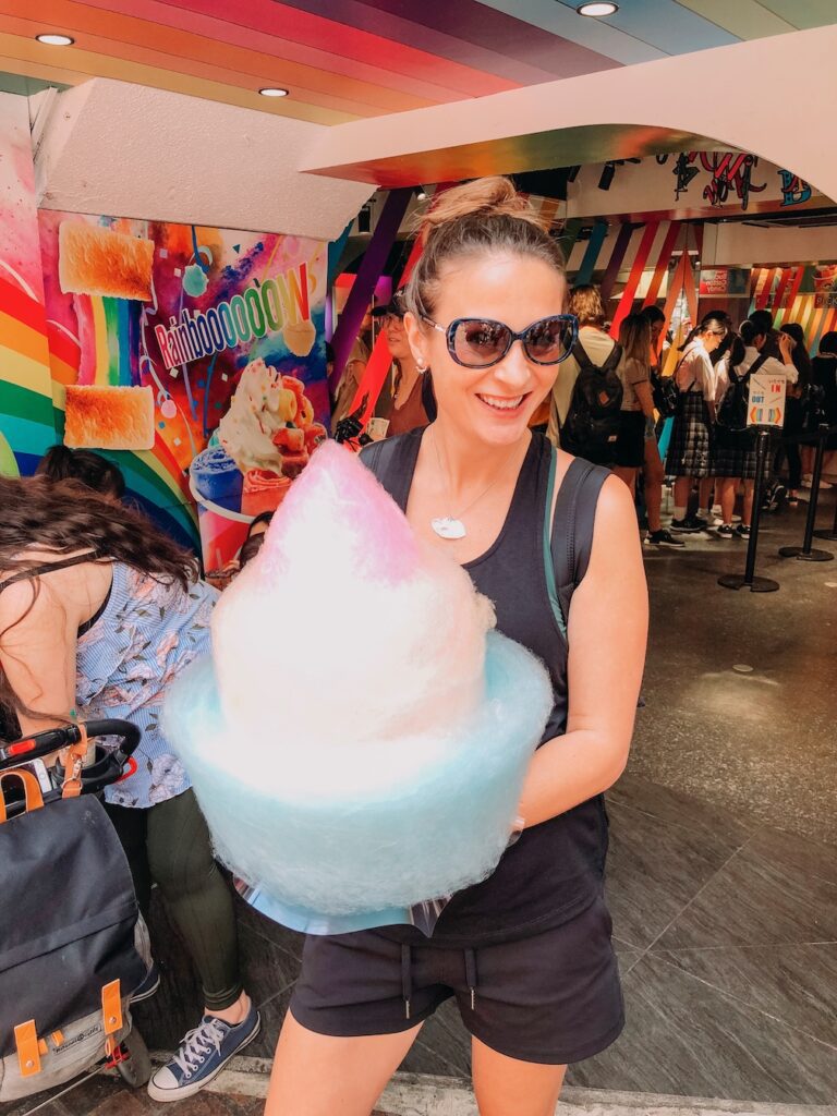 Bec eating a huge cone of multi coloured fairy floss on the street in Harajuku in Tokyo, Japan.