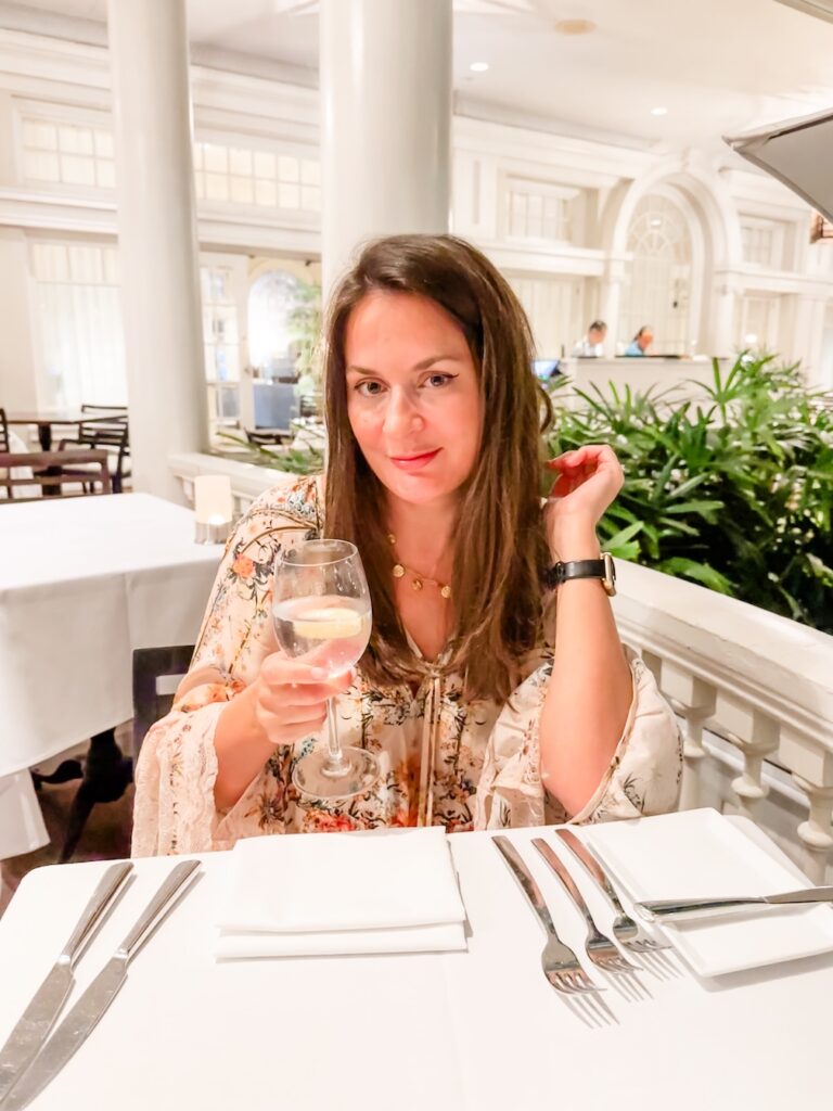 Travel writer, Bec Bowman sitting in the outside Verandah Restaurant at the Beachhouse at the Moana Restaurant. Beautiful Victorian architecture is visible in the background.