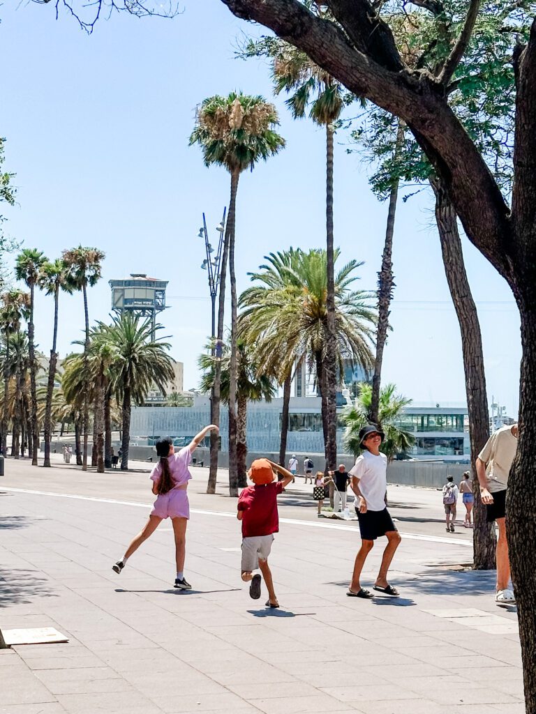 Kids chasing bubbles beside the marina in Barcelona, Spain in the summer heat. All wearing sunhat, shorts and t-shirts.