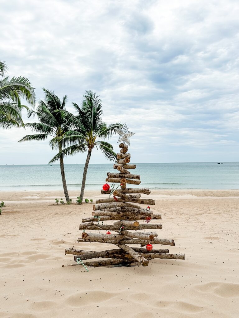 A driftwood christmas tree on the beach at Crowne Plaza Phu Quoc Starry. The white sand beach is immaculate, with perfect green palm trees standing in the background 