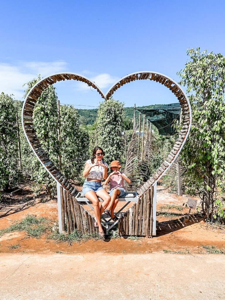 A mother and son make love heart hands while sitting on the love heart bench at Doc Thanh Pepper Farm in Phu Quoc.